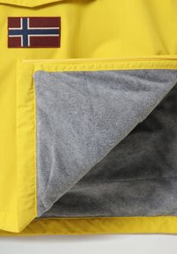 Gul vandtæt jakke med en norsk flagmærke, med en blød grå fleeceforing og synlig lynlåsdetalje.