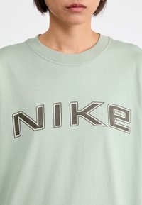 Ljusgrön oversized sweatshirt med en dj ärv, grå "NIKE"-logotyp över bröstet. Mjuk tyg med ribbat halsdetalj.