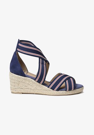 Tumedate espadrillide talvejalats, millel on ristuvad kangast rihmad punase ja valge triibuga. Kootud jute konts ja tekstureeritud sisetald.