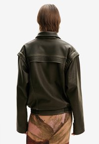 Dark green leather jacket with a structured collar, quilted back panel, and relaxed fit; features cinched waist and shoulder detailing.