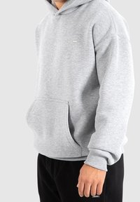 Sweat-shirt gris à capuche, avec une poche avant et des poignets côtelés. Tissu doux et design décontracté avec un petit détail de logo sur la poitrine.