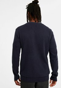 Marineblaues Sweatshirt mit langen Ärmeln, gerippten Bündchen und Saum, aus einem strukturierten Strickstoff gefertigt. Hat einen Rundhalsausschnitt und Raglanärmel.
