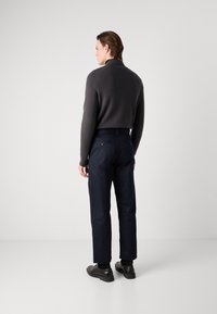 Mørkegrå genser med rund hals, marineblå bukser med baklommer og svarte sko. Enkelt design med en komfortabel passform og teksturert stoff.