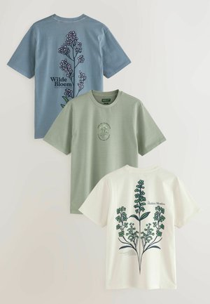 Drei Baumwoll-T-Shirts in Blau, Grün und Weiß mit floralem Design auf der Rückseite, einschließlich Text und Illustrationen, die Pflanzenmotive hervorheben.