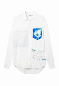 Camicia bianca con bottoni, caratterizzata da una tasca floreale blu, un motivo a righe su un lato e testo scritto a mano nella parte inferiore. Tessuto morbido.