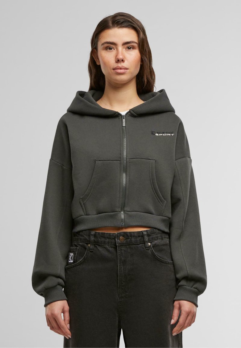 Felpa con cappuccio tagliata in misto cotone verde scuro, con zip frontale, tasche a marsupio e un logo discreto sul petto.