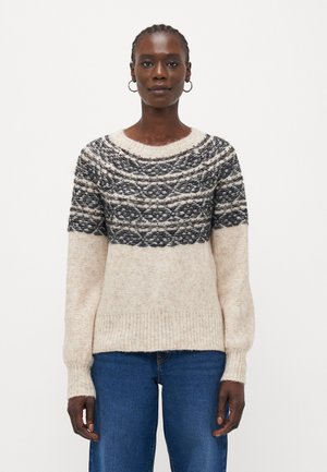 Beige ullgenser med svart mønster på bærestykket, rund hals og lange ermer. Strukturert overflate og ribbestrikkede mansjetter og nederkant.