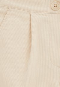 Beež corduroy kangas, millel on vertikaalsed ribad, ees plekk ja heleda tooni nööpdetail vööl.