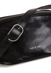 Sac bandoulière en cuir noir avec boucle et fermeture éclair argentées, arborant le logo "nat & nin" à l'avant.