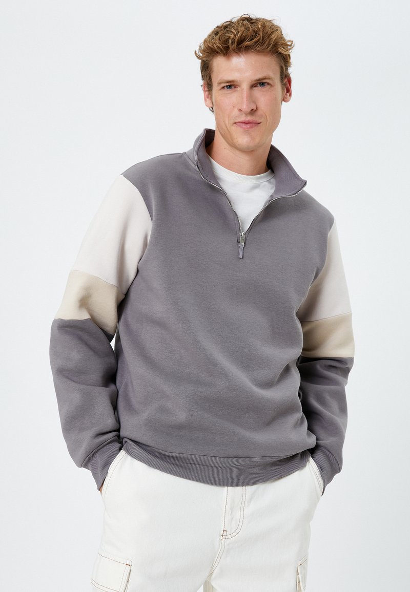 Grijs zip-neck sweatshirt met beige gekleurde blokmouwen, gemaakt van zachte stof. Kenmerkt zich met een geribbelde onderrand en manchetten, casual pasvorm.