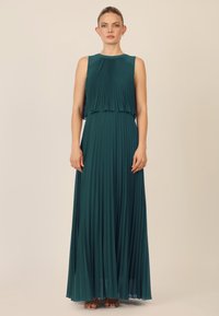 Geplooide, vloerlange jurk in diep teal, met een mouwloos ontwerp en gelaagde lijfje. Gemaakt van lichtgewicht stof met een gladde textuur.