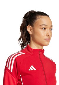 Rote sportliche Zip-Jacke mit weißen Streifen auf den Schultern und Branding; verfügt über einen hohen Kragen und eine figurbetonte Passform. Glattes, strukturiertes Gewebe.