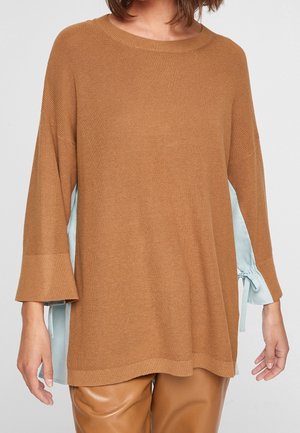 Pull en maille marron avec des manches larges, présentant un accent en tissu bleu clair sur les côtés, texture douce et coupe décontractée.