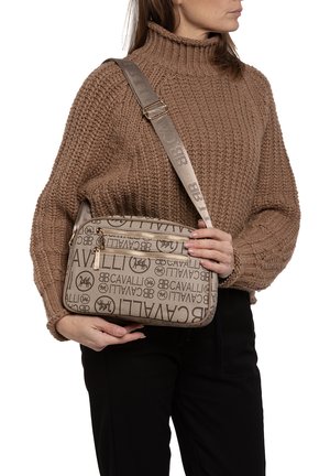 Borsa a tracolla beige con un tessuto testurizzato caratterizzato da un motivo logo ripetuto, hardware in tonalità oro e una tracolla regolabile.