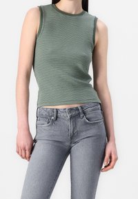 Haut sans manches à rayures vertes avec une coupe ajustée, associé à un jean gris clair taille haute doté de poches et d'une fermeture à boutons.