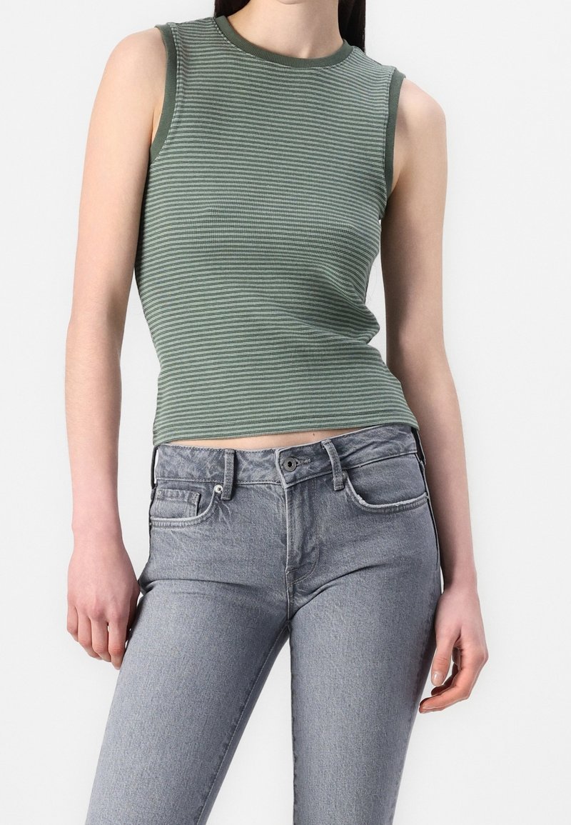 Haut sans manches à rayures vertes avec une coupe ajustée, associé à un jean gris clair taille haute doté de poches et d'une fermeture à boutons.