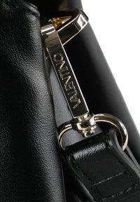 Dettaglio di una borsa in pelle nera con chiusura e accessori in metallo argentato lucido, che mette in mostra una superficie strutturata e un design lussuoso.