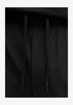 Schwarze Sportshorts mit einer perforierten Oberfläche und flachen Kordeln. Der Bund ist elastisch und sorgt für einen engen Sitz.