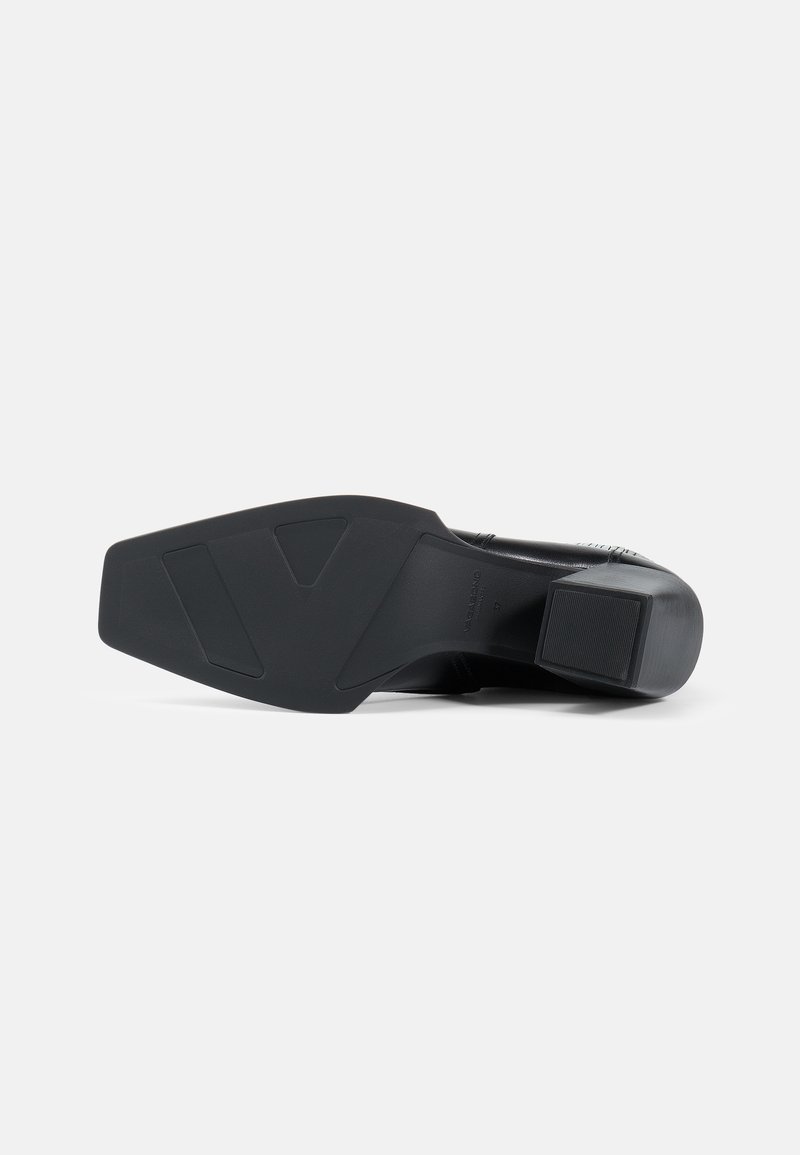 Black heeled shoe with a smooth leather upper, rounded toe, sturdy block heel, and a textured rubber sole featuring a geometric pattern.