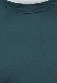 Türkiz pulóver bordázott kerek nyakkal, puha, texturált anyagból készült, látható minták vagy grafikák nélkül.