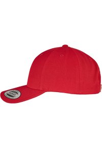 Rød baseballkasket med flad skygge, lavet af tekstureret stof. Har syningsdetaljer og et cirkulært mærke på siden.