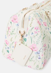 Blomstrete duflebag med hvitt syntetisk materiale; har rosa og blå blomster, gull hardware, doble glidelåser og en avtagbar merkelapp.