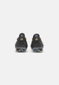 Zwarte sportieve schoenen met een gladde textuur, voorzien van een twee-kleuren ontwerp, opvallende hielsteun en gouden merkaccenten aan de achterkant.