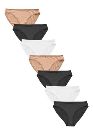 Kvinde iført matchende beige bh og trusser, stående mod en ensfarvet neutral baggrund med armene bag ryggen.