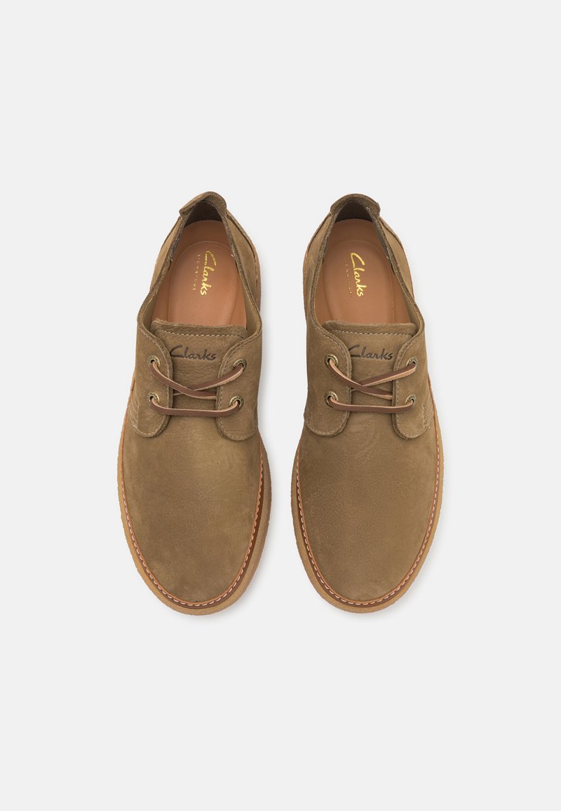 Scarpe stringate in suede marrone con dettagli cuciti e design a punta rotonda, dotate di lacci beige e un inserto con brand.