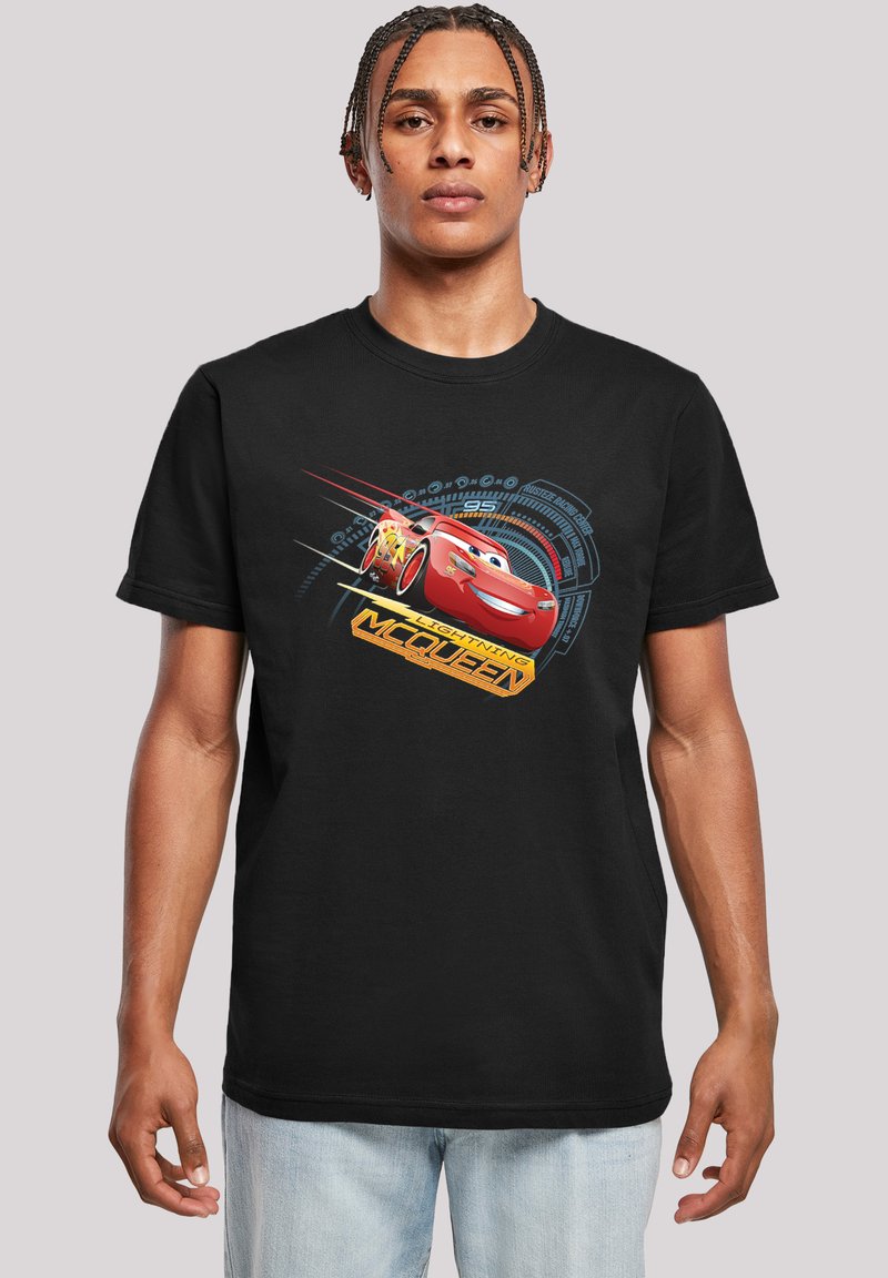 Melnā T-krekliņš ar Lightning McQueen grafiku sarkanā un dzeltenā krāsā, ar ziliem ģeometriskiem akcentiem un apaļu kakla izgriezumu.