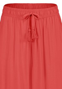 Coral wide-leg pants made of lightweight fabric with an elastic waistband and a drawstring tie featuring tassel accents.