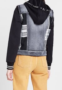 Jeansjacka och svart hoodie med en sliten textur, rutmönstrade detaljer och ribbade ärmar. Justerbar huva med textdetalj.