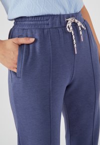 Blaue Sport-Jogginghosen mit elastischem Bund, verstellbarem Kordelzug, seitlichen Taschen und weichem, strukturiertem Stoff.