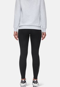 Black leggings with a smooth texture, featuring a fitted design and knee panels, worn with a light gray sweatshirt and sporty shoes.