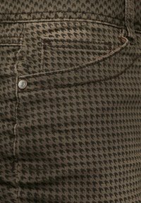 Hnědé džíny s kostkovaným vzorem ve stylu houndstooth s detailním pohledem na kapsu, měděný nýtek a texturovanou látku. Obsahují detaily prošíván�í a mají slim fit.