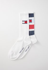 Fehér, bokáig érő zoknik, bordázott mintázattal. Az egyik zoknin színes csíkos minta található; mindkettőn a "TOMMY JEANS" logó látható.
