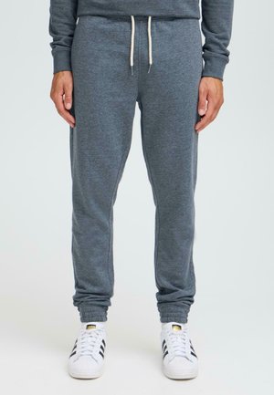 Grijze katoenen joggers met een elastische tailleband en trekkoord, met taps toelopende boorden en een zachte textuur. Gecombineerd met witte sneakers.