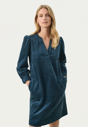 Teal corduroy dress with a V-neck, long puffed sleeves, side pockets, and a relaxed silhouette. Smooth texture with vertical ribbing.