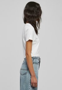 Hvit kortermet, cropped t-skjorte laget av bomull, sammen med falmede blå høyhøydde denimjeans med en lett slitt tekstur.