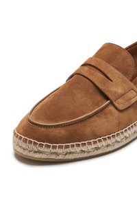 Mocasines de ante marrón con detalle de costura, suela de yute trenzado y un diseño de punta redondeada y suave.