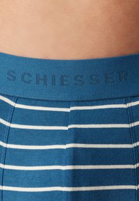 Boxer shorts a righe blu con una vita morbida che presenta il marchio in rilievo "SCHIESSER." Le righe sono bianche su un tessuto blu.