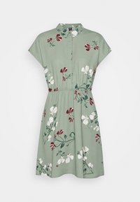 Kortärmad klänning med krage i ljusgrönt med ett blommönster i röda, vita och gröna accenter; midjan är markerad för en definierad form.