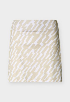 Jupe-short beige avec un motif en zigzag blanc. Fabriquée dans un tissu lisse et extensible. Dotée d'une taille ajustée et d'un ourlet droit.