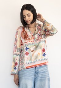 Langärmlige Bluse mit buntem, abstraktem Tierdruck; aus leichtem Stoff mit einer Knopfleiste am Ausschnitt und ausgestellten Manschetten.