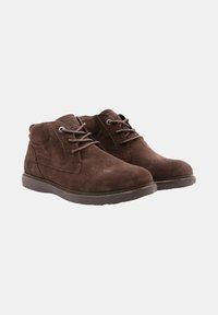 Bottines en suede marron, avec un bout rond, un laçage et une surface texturée. Comprend une semelle en caoutchouc et des accents de couture.