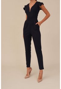 Marintrumpet med djup V-ringning och volangärmar, skräddarsydd passform, smalnande ben och sidofickor, tillsammans med nakna högklackade skor.