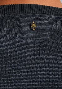 Tmavohnedý pletený sveter s rebrovaným výstrihom a malou čiernou a zlatou nášivkou "PME Legend" na chrbte. Hladká textúra.