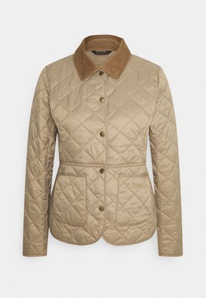 Beige gewatteerde jas met een corduroy kraag, voorzien van drukknoopsluitingen, twee voorzakken en subtiele branding aan de onderlinkerkant.