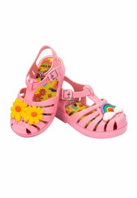 Sandali in gomma rosa con un design floreale caratterizzato da fiori gialli e un accento arcobaleno sul davanti. Design a fascia con chiusura con fibbia.