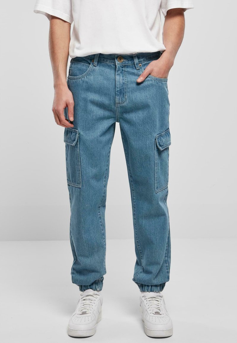 Lys blå denim cargo bukser med elastiske manchetter, to sidelommer og en klassisk pasform. Båret med en afslappet hvid t-shirt og hvide sneakers.